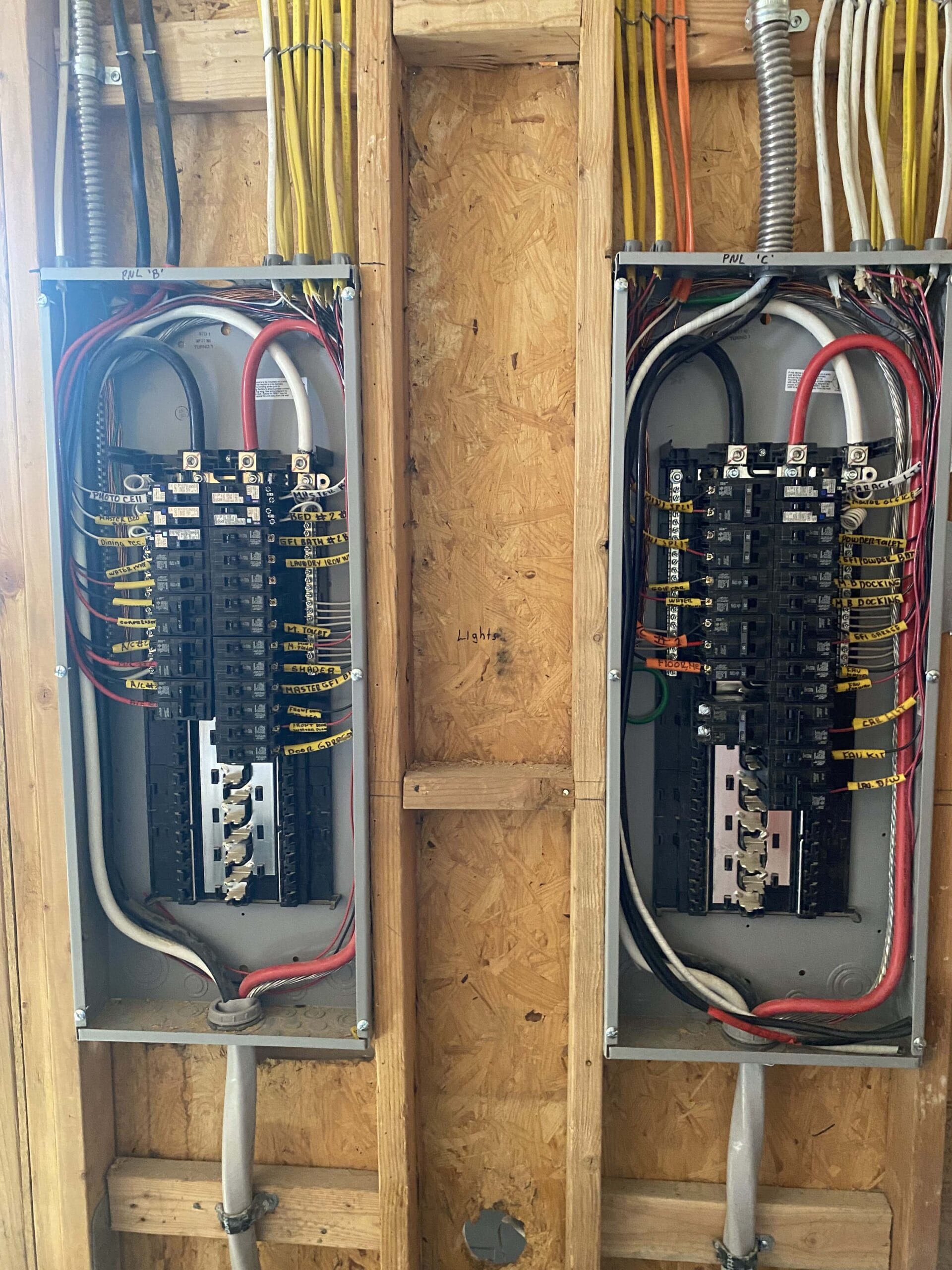IMG3371 Clark Electric LV LLC Clark Electric LV LLC Two residential electrical panel boxes with organized circuit breakers wiring and conduit installations in a wooden wall cavity