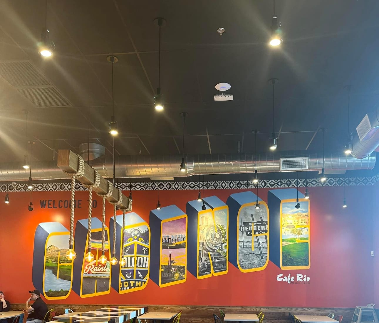 Modern indoor sports facility with bright LED lighting fixtures illuminating an orange accent wall featuring vintage neon style signage