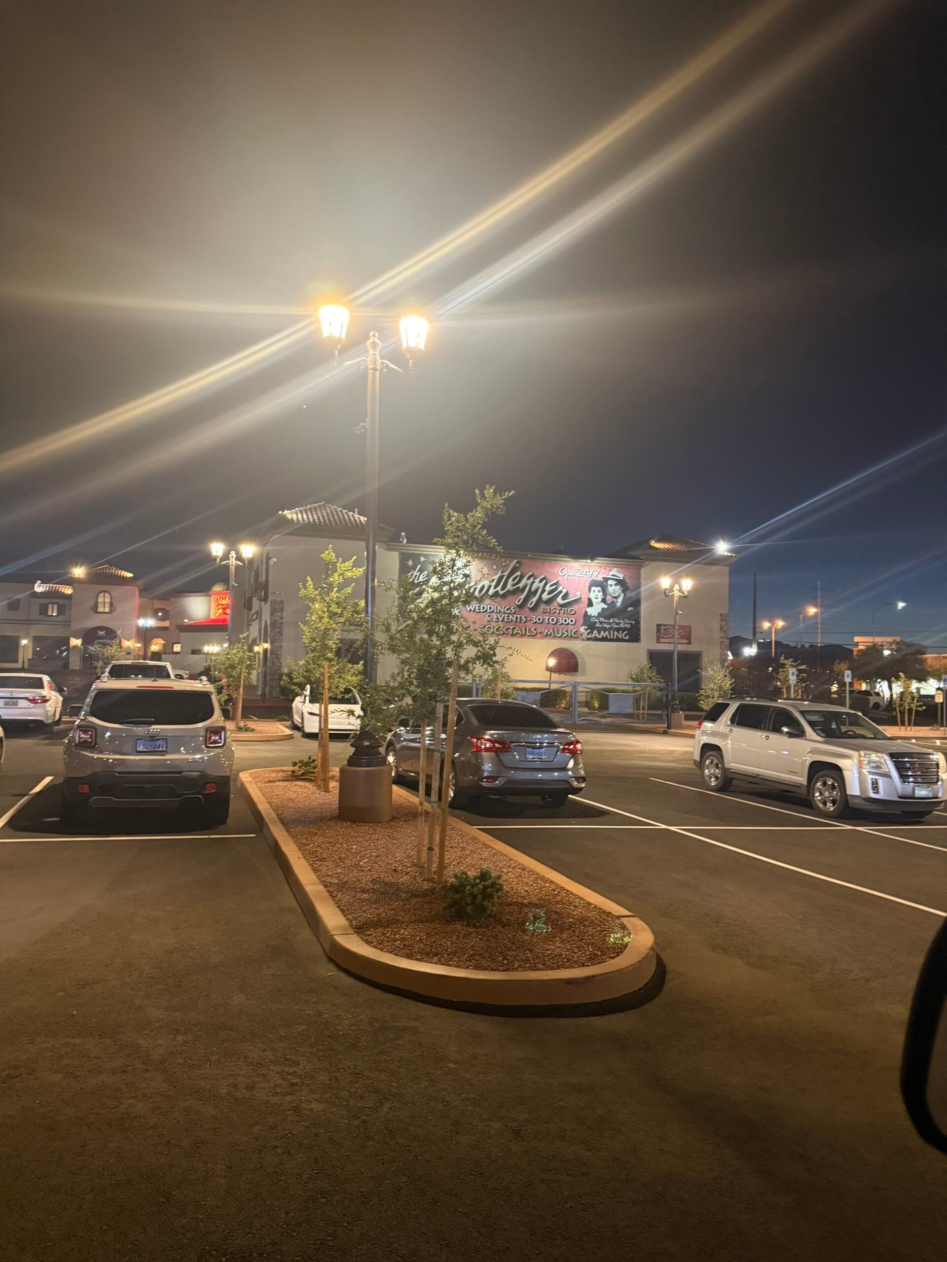 Night parking lot illuminated by bright commercial LED lighting fixtures mounted on tall poles