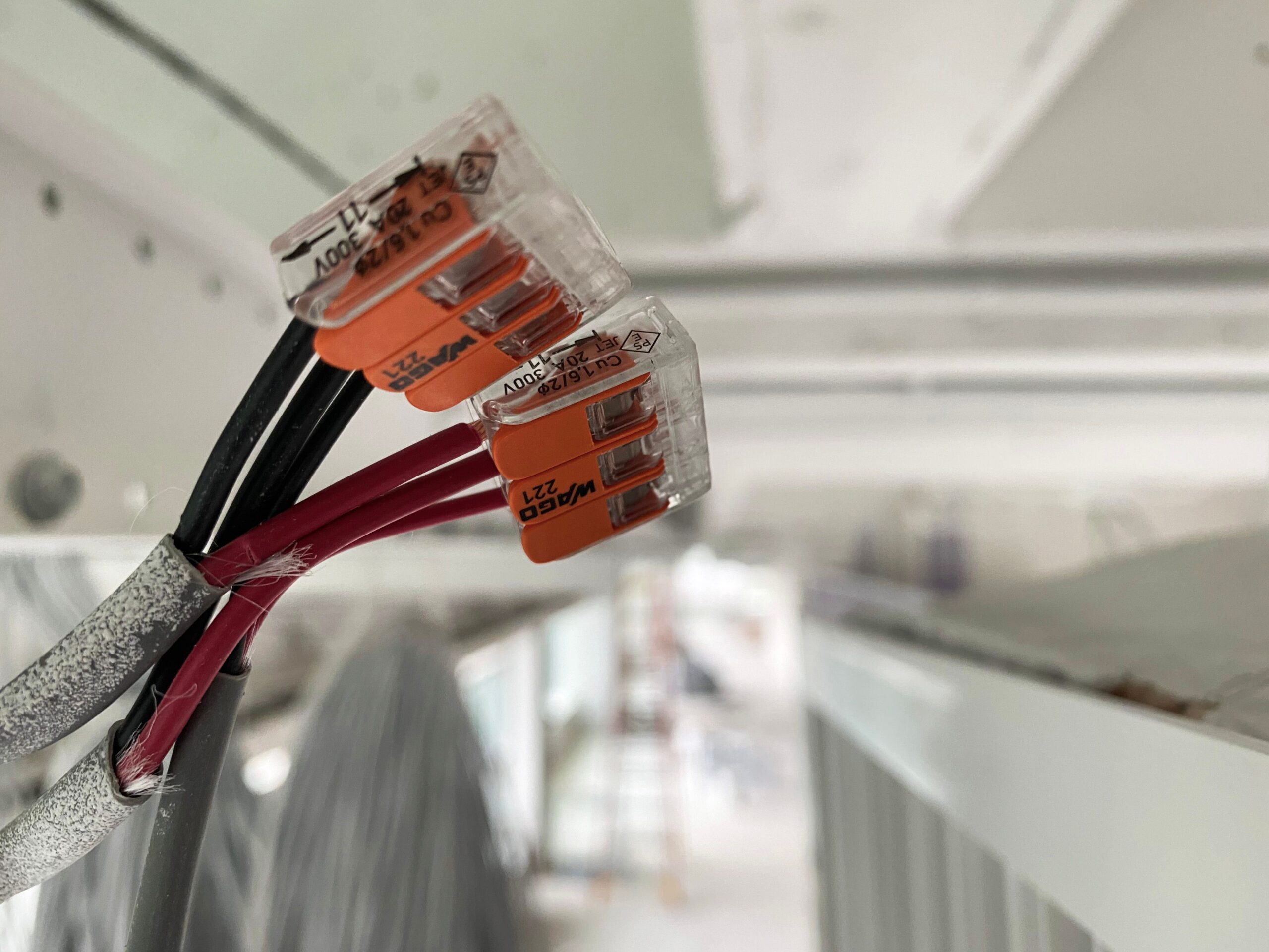 Close up of orange terminal blocks on red and black wires attached to a metal bar with a blurred background