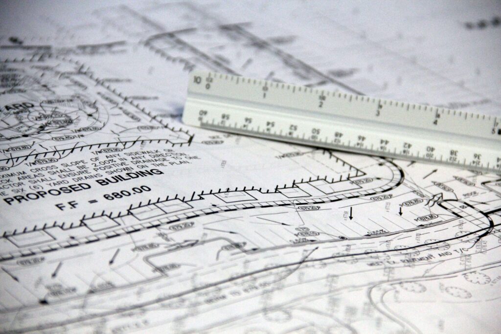 Architectural blueprints with a measuring ruler across the plans on a desk or floor