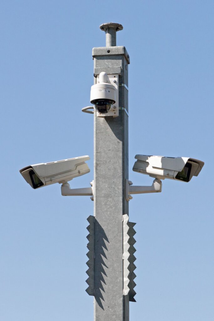 Security camera system mounted on concrete pole with multiple surveillance cameras against clear blue sky
