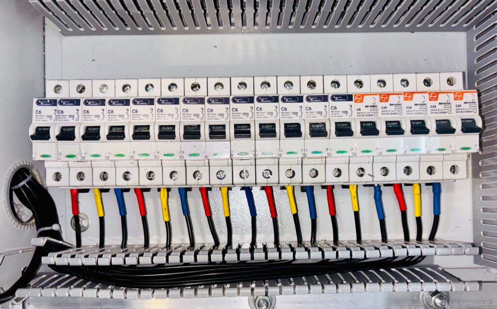 Electrical distribution panel with multiple circuit breakers and colored wires connected to terminals